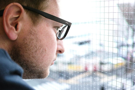 a man in glasses looking at the traffic out of the window with copy space on the rightの写真素材