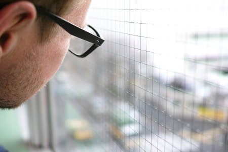 a man in glasses looking at the traffic out of the window with copy space on the rightの写真素材