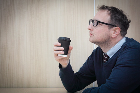 A man looking thoughtful during his break while drinking his coffee.の写真素材
