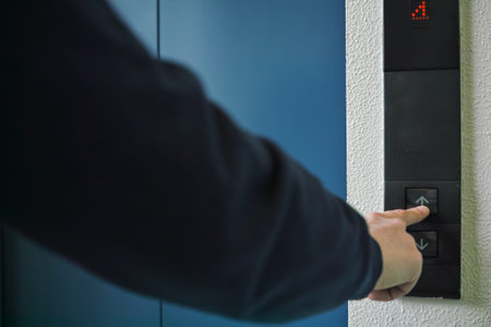 A rear view of a man pushing an elevator button with his index finger