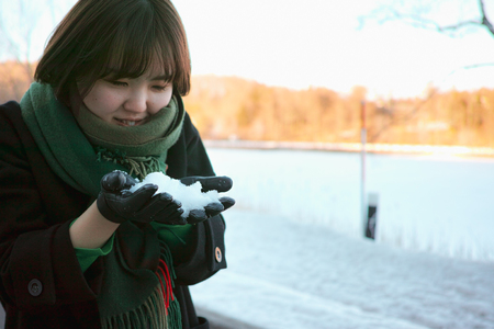 A fashionable young woman playing with snow in the winterの写真素材