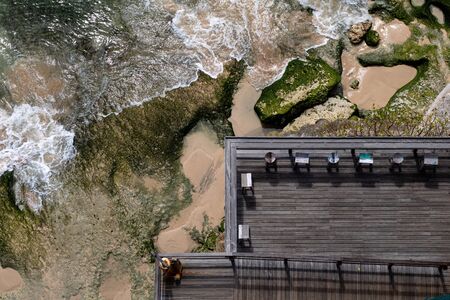 Aerial view of a decked seating area on a beach with a the sea coming inの写真素材
