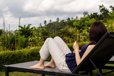 A young woman relaxing on a deck chair at a tropical destinationの写真素材