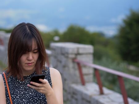 A Japanese woman walking while looking at her phoneの写真素材