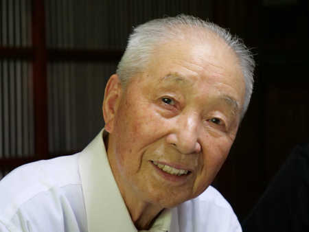 A portrait of an elderly Asian man smiling into the camera.
