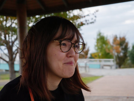 A pretty young asian woman smiling while sat outdoorsの写真素材