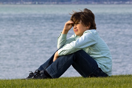 a boy sitting on seacoast and looking in distanceの写真素材