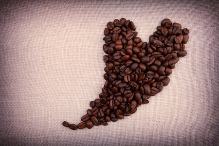 Dark roasted coffee beans  in the shape of a heart on fabric backgroundの写真素材