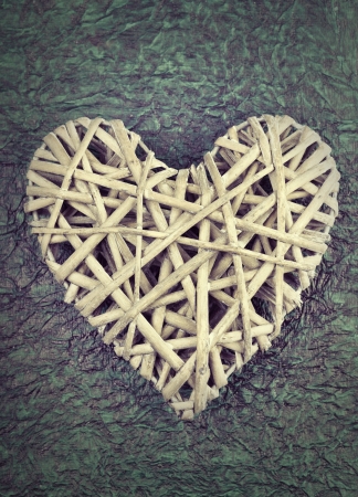 A handmade heart made from twigs on crumpled green paperの写真素材