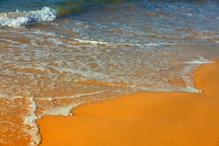 Golden sand and sea waves background の写真素材