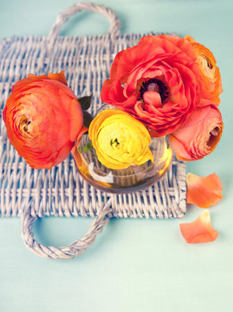 Ranunculus flower on a wicker tray on vintage background