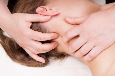 A woman getting a stress relieving pressure point massage on her neck by a therapistの写真素材