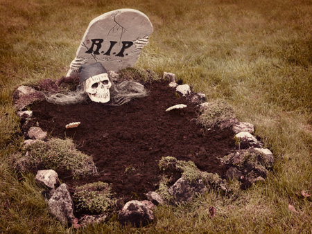 Skull with hands reaching from the grave  Decoration in a garden for halloweenの写真素材