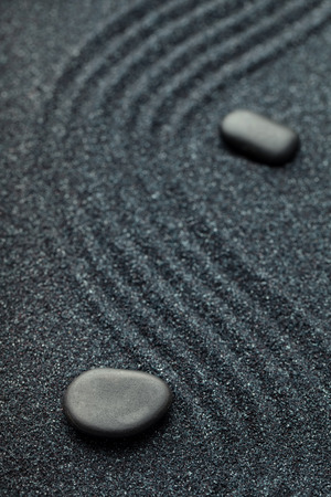 Zen garden with a wave lines in the sand with relaxing black stonesの写真素材