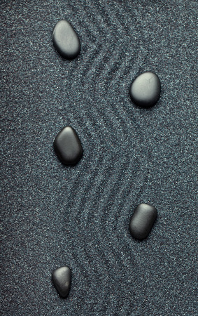Zen garden with a wave lines in the sand with relaxing black stonesの写真素材