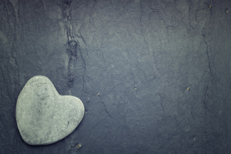Gray zen heart shaped rock in the corner on a tile backgroundの写真素材