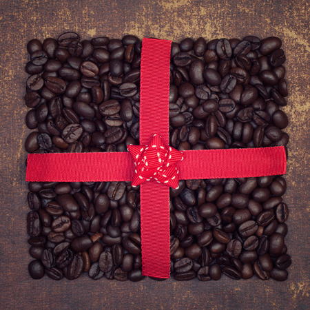 The shape of a present made out of roasted coffee beans  on shabby chic surfaceの写真素材
