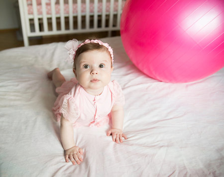 Little sweet girl plays with fitness ball on a white background. Healthy lifestyle. Gymnastics for...