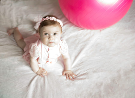 Little sweet girl plays with fitness ball on a white background. Healthy lifestyle. Gymnastics for...
