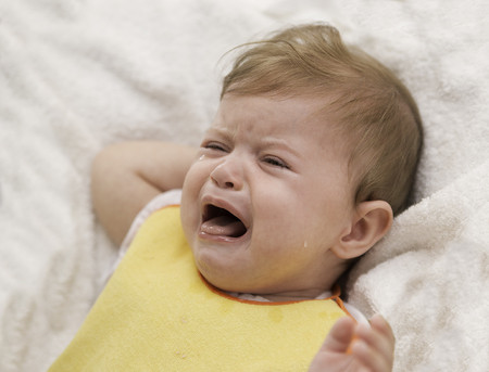 The baby in a bip is crying and refuses to eat. Child's hysterics. Closeup portrait of crying baby.の写真素材