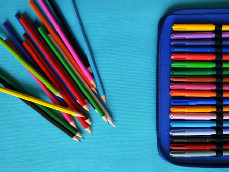 Back to school concept. Top horizontal view of school supplies on blue background. Color pencils piled and case with markers.の写真素材