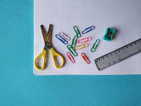 Back to school concept. Top horizontal view of school supplies on blue background. Scissors, sharpener, clips, ruler and notebook.の写真素材