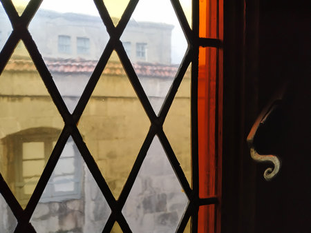Stained glass window with vintage lock closeup. Looking at the view of an old building