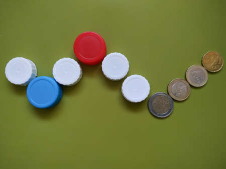 Plastic recycling concept generating finance profit. Caps and coins on green background.の写真素材