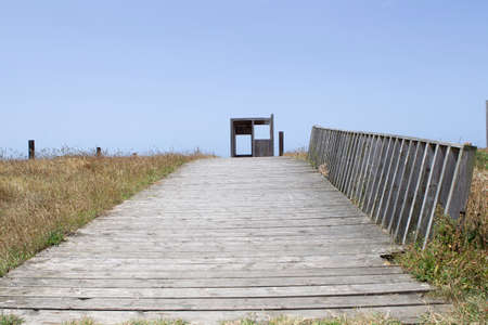 Wooden walkway with hut in the background and blue sky in the background.の写真素材
