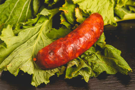 Chorizo ââsausage on black slate with turnip greens in the backgroundの写真素材