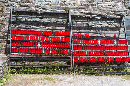 Offerings in the form of a red candle with lighted lights at the door of the Santuario Santa Maria a real in O Cebreiro, Lugo, Spain, on the way to Saint Jamesの写真素材