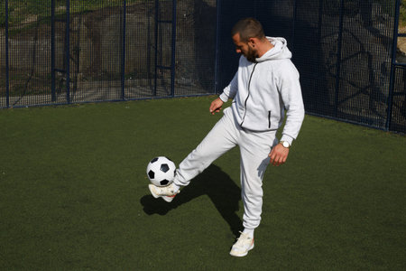 Young male soccer player juggles a ball on a soccer field