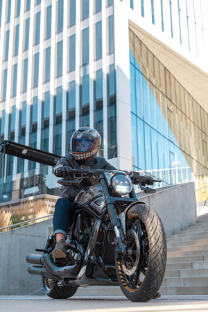 Handsome biker with helmet sitting on his moto against urban backdrop. high quality photoの写真素材