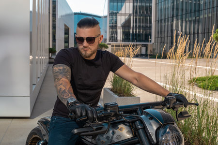 Handsome motorcyclist in sunglasses on his moto against an urban backdrop riding in the city. high quality photoの写真素材