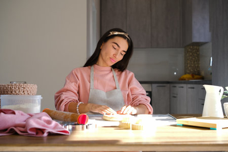 Lifestyle, cooking and freelance concept: Young woman baking cookies standing in her apron in kitchen at home. high quality photoの写真素材