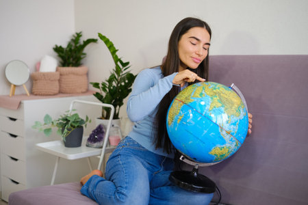 Traveling concept, Asian beautiful woman looking at globe ball in the bright room. high quality photoの写真素材