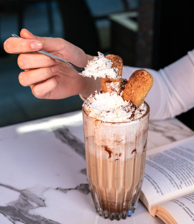 Woman enjoying tiramisu iced coffee with cream and biscuitsの写真素材