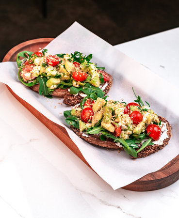 Avocado Feta Bruschetta with Arugula and Cherry Tomatoes on Multigrain Breadの写真素材