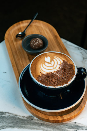 Delicious mocha coffee with heart shaped latte art and chocolate shavings. Served on a wooden tray...