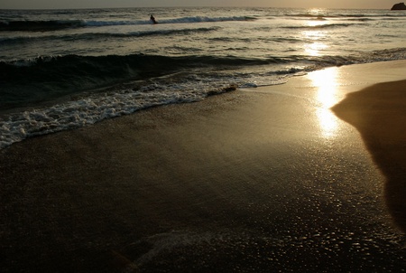 Greek sunrise with wave on beachの写真素材