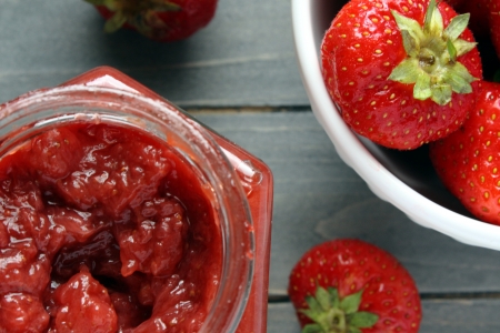 Strawberry jam in a jar on a wooden table and strawberriesの写真素材