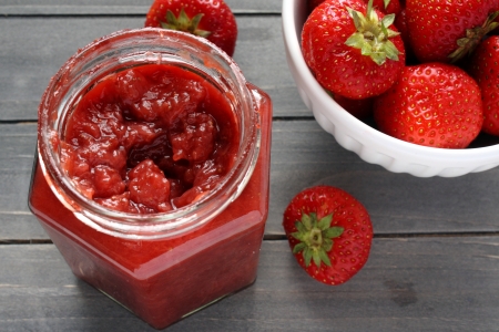 Strawberry jam in a jar on a wooden table and strawberriesの写真素材