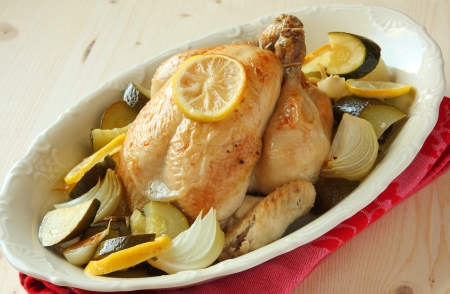 Roasted whole chicken with lemon, zucchini and onionsの写真素材