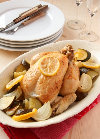Roasted whole chicken with lemon, zucchini and onionsの写真素材