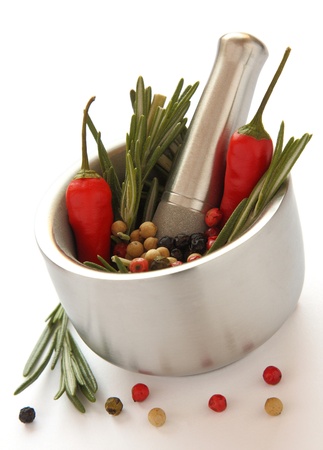 Fresh rosemary herb and red pepper in metal mortar with pestle on white backgroundの写真素材