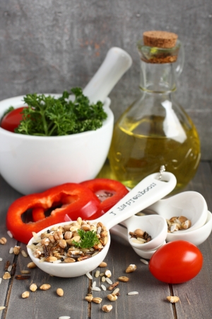 Uncooked multigrain rice in porcelain measuring spoons  with raw vegetableの写真素材