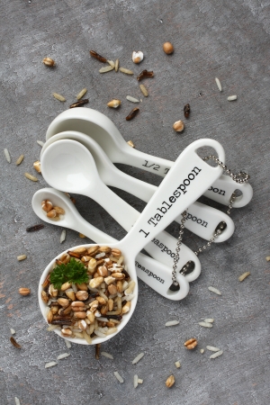 Uncooked multigrain rice in porcelain measuring spoons on wooden の写真素材