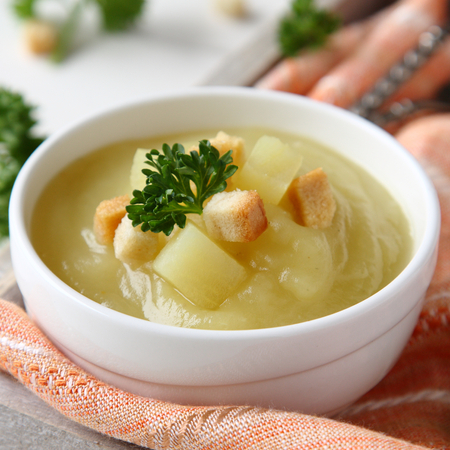 Creamy sweet potato soup with croutons and parsley in white bowlの写真素材