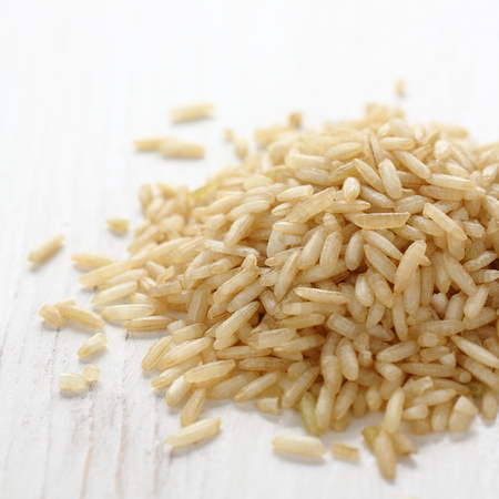 Pile of brown rice grain on white wooden backgroundの写真素材