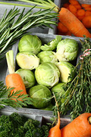Fresh raw brussels sprouts, carrots, rosemary, thyme and parsley in wooden boxの写真素材